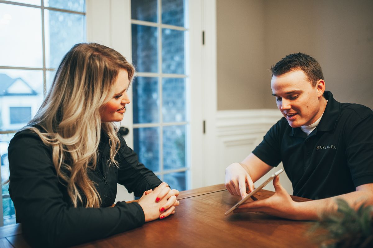 An Urbanex technician walking a homeowner through details on a tablet at her kitchen table