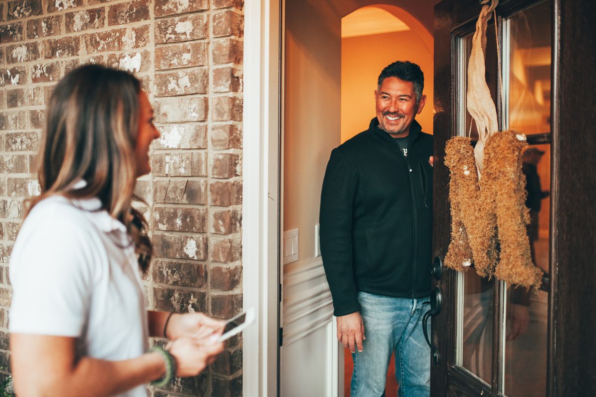 A smiling homeowner opening his front door to an Urbanex technician