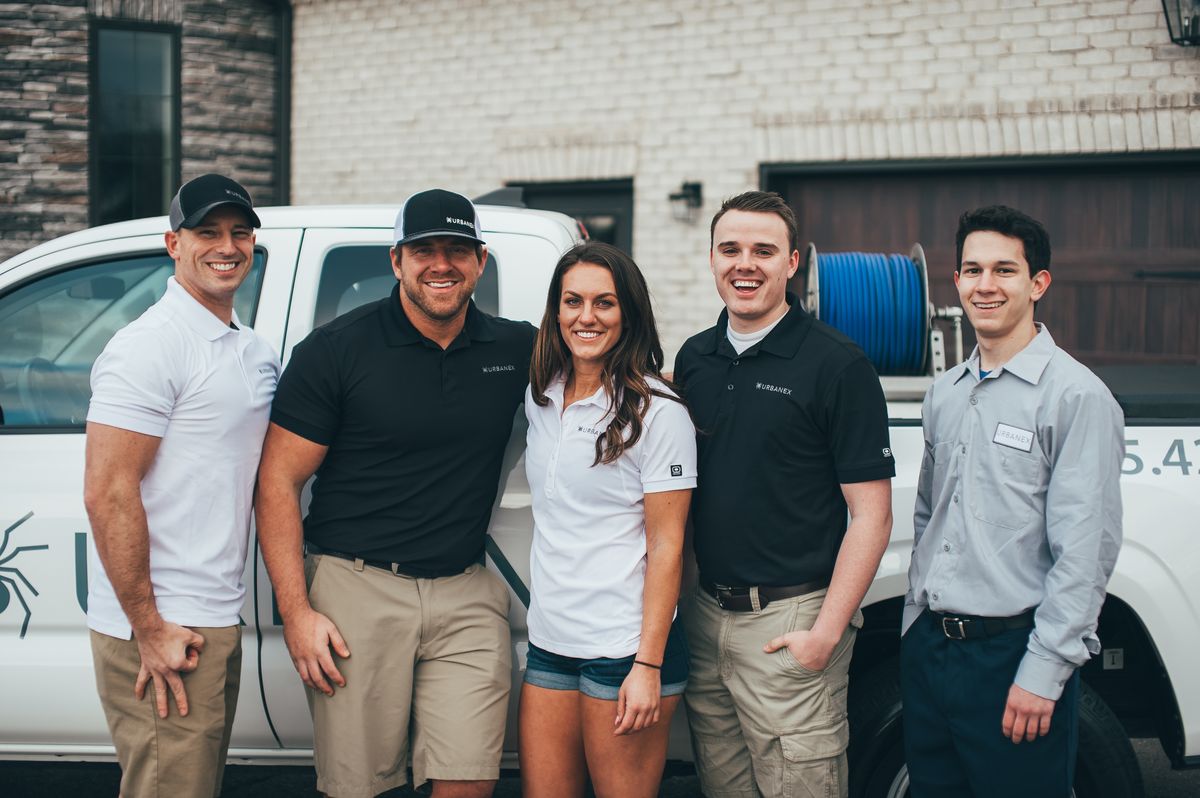 Five Urbanex team members standing together in front of an Urbanex service truck