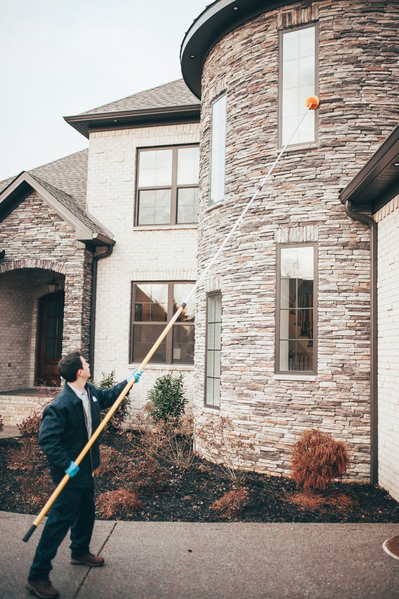 An Urbanex technician treating the second-story eaves of a home with an extension pole