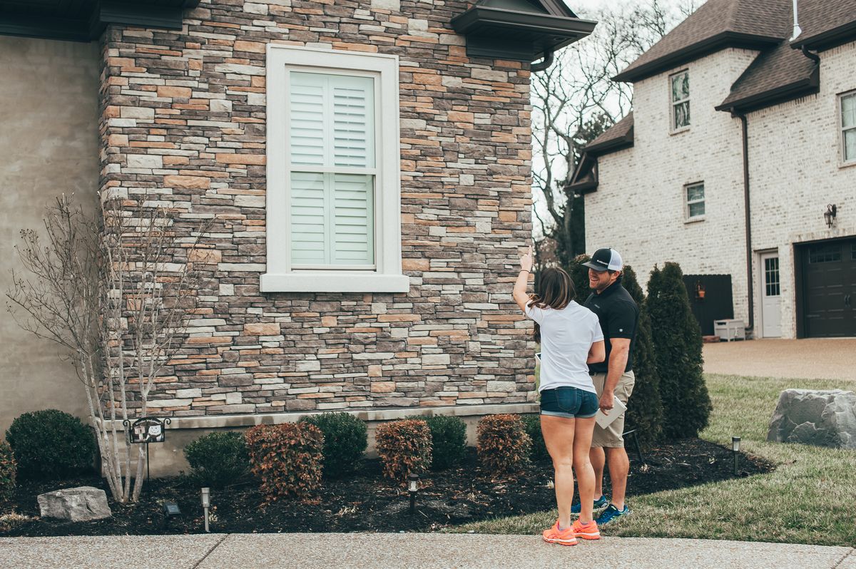 An Urbanex technician walking a home's exterior with the homeowner, checking the structure